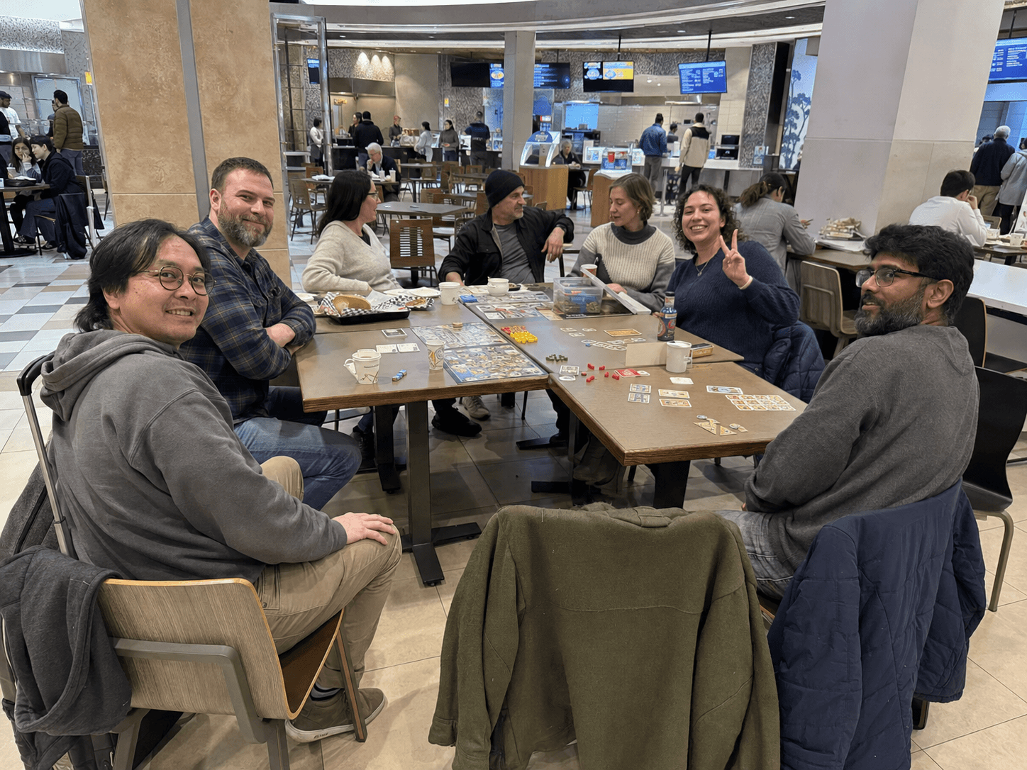 Friends gathered around board games at a mall food-hall meetup.